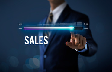 Sales growth, increase sales or business growth concept. Businessman is pulling up progress bar with the word SALES on dark tone background.