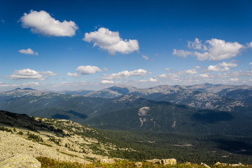 Rocks under blue sky with clouds. View of mountain valley. Tourism, travel to mountains.