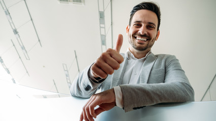 Happy business man shows thumb up sign gesture.
