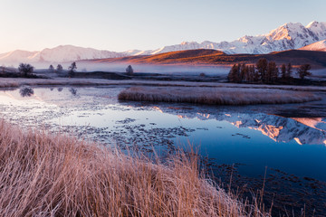 Reflection of snowy mountain ridge in lake. Autumn in mountains. Travel Altai.