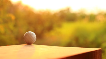 Golf ball on wood with sunset.