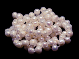 Thread of natural white baroque pearl beads on black background