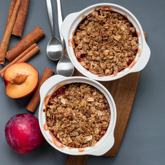 Plum crumble pie or plum crisp with oats and spices, in baking dish, top view, square format