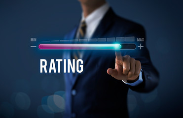 Increase rating, rating raised or business growth concept. Businessman is pulling up progress bar with the word RATING on dark tone background.