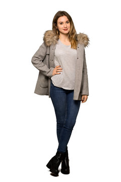 A full-length shot of a Teenager girl with coat posing with arms at hip and smiling on isolated white background