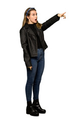 A full-length shot of a Teenager girl with leather jacket pointing away on isolated white background