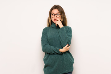 Teenager girl over white wall having doubts while looking up