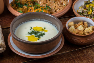 Middle Eastern cuisine dishes in ceramic plates on a wooden table. Soup with Greek yogurt, chicken...