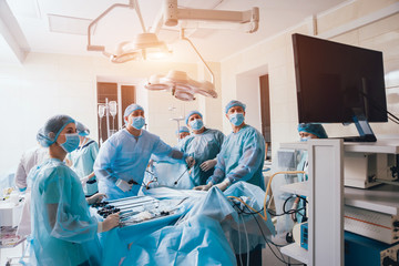 Process of gynecological surgery operation using laparoscopic equipment. Group of surgeons in operating room with surgery equipment