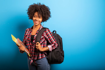 young african student with backpack on the back on blue background