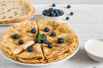 Homemade crepes or thin pancakes served with fresh blueberries, sour cream and mint
