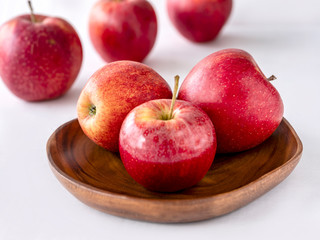 Six red apples on the wooden plate and white background