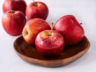 Six red apples on the wooden plate and white background