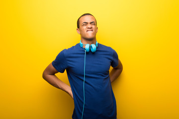 African american man with blue t-shirt on yellow background suffering from backache for having made an effort