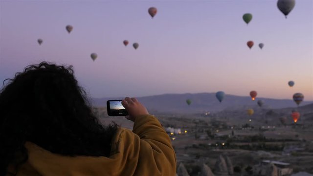 woman shoots Cappadocia air balloons on the phone