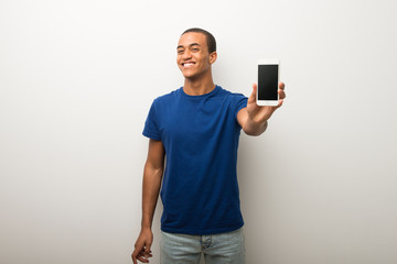 Young african american man on white wall showing the mobile