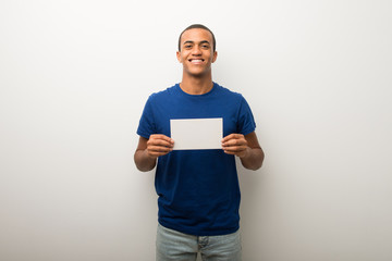 Young african american man on white wall holding a placard for insert a concept