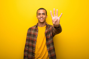 Young african american man on vibrant yellow background happy and counting four with fingers