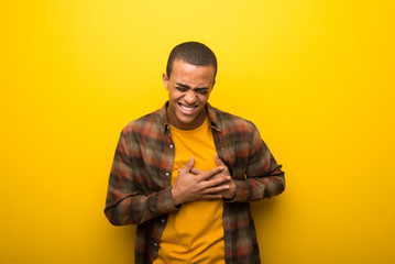 Obraz premium Young african american man on vibrant yellow background having a pain in the heart