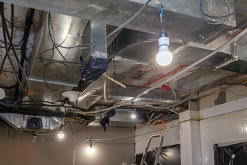 Installation and repair of frame, ventilation system, fire alarm, electric cable, lamp bulb before assembling stretch or suspended ceiling. Concept of reconstruction in office building