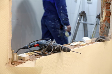 Closeup professional construction dusty drill, puncher on background of workman, building tools. Concept installation and dismantling windows and doors in office building