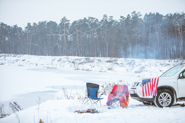 camping concept. bonfire with two chairs near it. car with usa flag on the hood