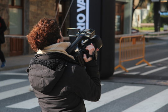 Mujer de mediana edad de espaldas sujetando cámara de vídeo o televisión en evento deportivo