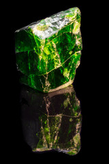 Crystal of natural green chrome diopside on black background with reflection