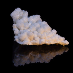 Natural druse of white calcite on a black background with reflection
