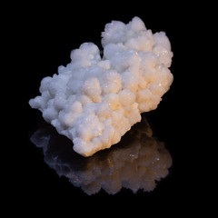 Natural druse of white calcite on a black background with reflection
