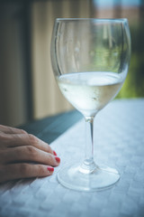 Drinking problem: Glass of white wine, hand of a woman with red nail polish