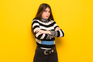Young woman over yellow wall making doubts gesture while lifting the shoulders