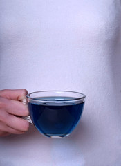 Blue tea anchan in a glass cup in female hands