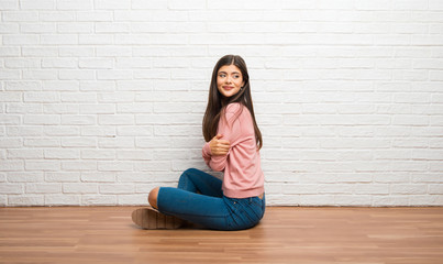 Teenager girl sitting on the floor in a room looking over the shoulder with a smile