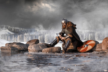 Medieval Scandinavian warrior Viking in full outfit on shore of winter sea