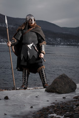 Medieval Scandinavian warrior Viking in full outfit on shore of winter sea