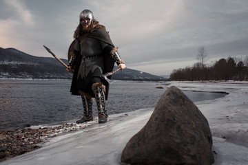 Medieval Scandinavian warrior Viking in full outfit on shore of winter sea