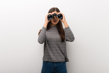 Teenager girl on isolated white backgorund and looking in the distance with binoculars