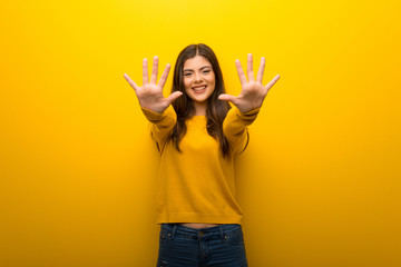 Teenager girl on vibrant yellow background counting ten with fingers - obrazy, fototapety, plakaty