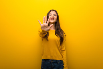 Teenager girl on vibrant yellow background counting five with fingers