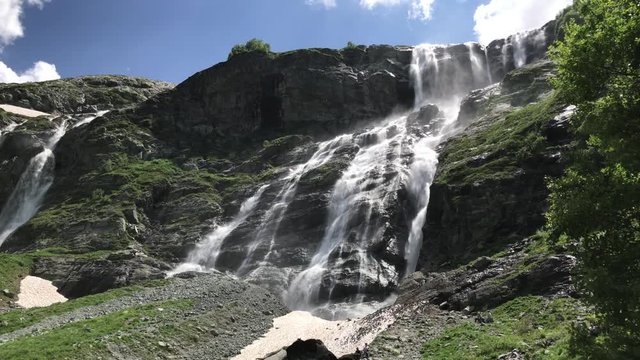 Sofia (Sophia) waterfalls in Caucasus mountains. Huge water stream falling from the high rock in a sunny summer day. Popular tourist destination. Arkhyz, Republic of Karachay-Cherkessia, Russia