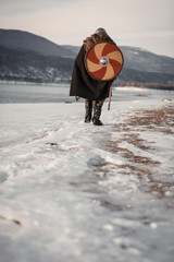 Medieval Scandinavian warrior Viking in full outfit on shore of winter sea