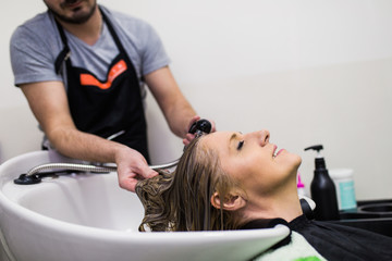 Obraz na płótnie Canvas Hairdresser washing hair of a beautiful mature woman in hair salon.