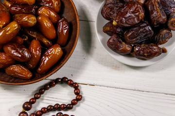 Dates fruit and rosary on white wooden table. Top view