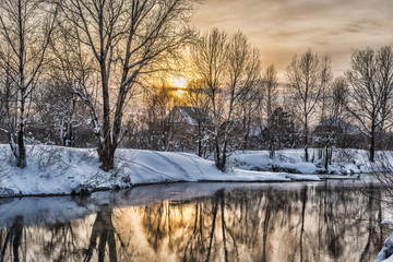Snowy frozen landscape of sunrise on lakeside with trees