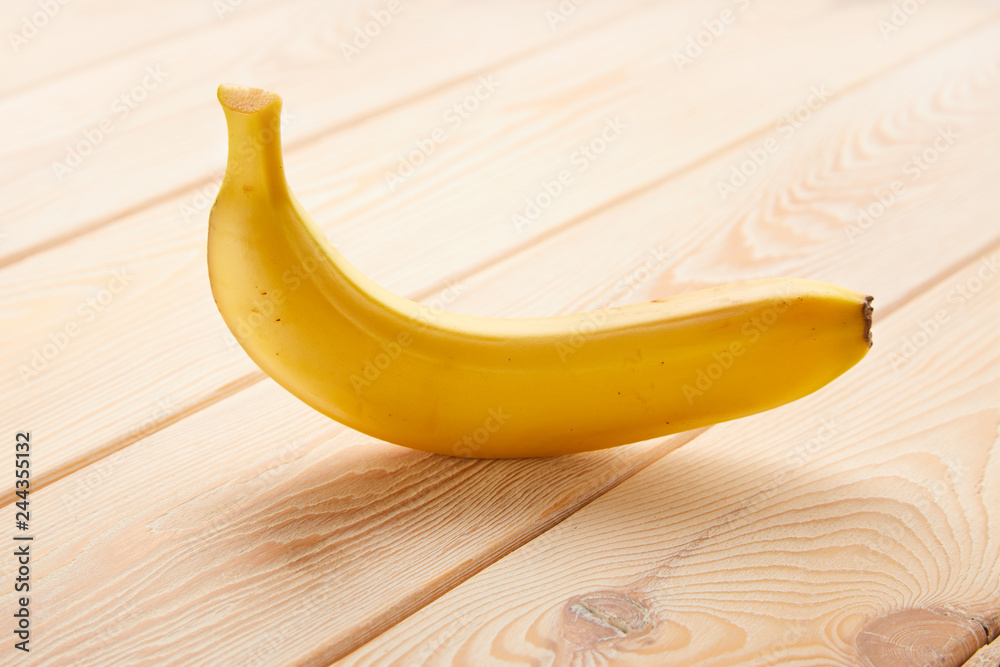 Wall mural image of single banana on wooden table