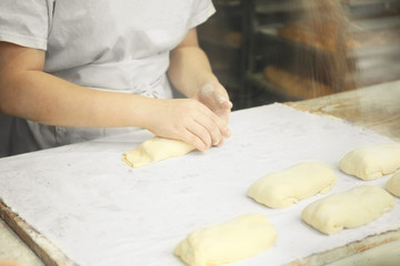 Women's hands preparing pies from raw dough.