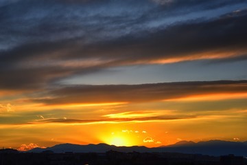 Tranquil panoramia scene of red sun and orange sky sunset over the Rocky Mountains in Colorado by Denver, United States.