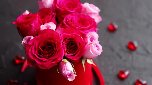 Pink roses bouquet packed in red box and placed on black stone background with copy space. Valentines day or Romantic concept.