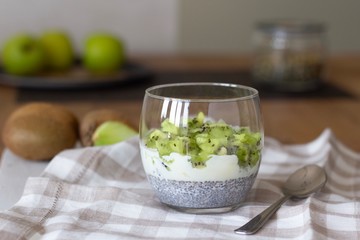 Well being and weight loss concept, healthy vegetarian fruit dessert with kiwi yogurt and chia seeds pudding in a glass, summer detox superfoods